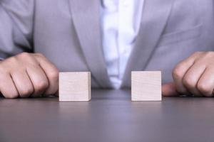 A businessman holds two wooden cubes with empty space for icons, free space for letters, numbers, symbols or labels. photo