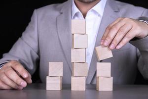 A businessman builds a pyramid of ten wooden cubes to write a word or phrase. Copy space photo