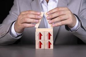 Wooden blocks in the form of a house with red upward arrows. The process of successful business and economic development. Increased productivity, planning, management and strategy. photo