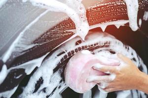 people man holding hand pink sponge for washing car. Concept car wash clean. photo
