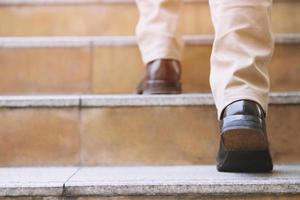 cerrar las piernas zapatos de un joven hombre de negocios una persona caminando subiendo las escaleras en la ciudad moderna, subir, tener éxito, crecer. con tonos de filtro efecto cálido vintage retro. escalera
