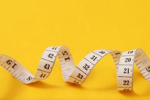 cinta métrica para personas obesas con un enfoque suave de fondo amarillo foto