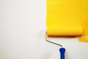 pintura con cepillo de rodillos, trabajador en el apartamento de la pared de la superficie, renovando con pintura de color amarillo. deje el espacio de copia vacío en blanco para escribir un texto descriptivo al lado. foto