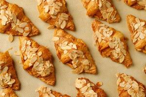 freshly baked croissants set of delicious fresh in wax paper plates on wooden dark table. French breakfast. top view Copy space. photo