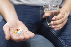 close up hand man holding taking multiple pills. Stop drug use Taking Medication health care medical concept. photo