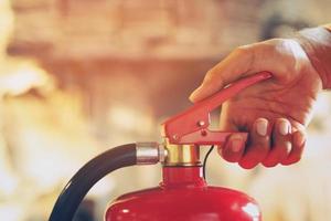 hand presses the trigger fire extinguisher available in fire emergencies conflagration damage background. Safety photo