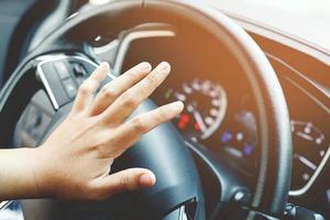 person pushing horn while driving sitting of a steering wheel press car, honking sound to warn other people in traffic concept. photo