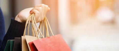 Close up of consumerism young woman holding hand many shopping bag in fashion boutique after buying presents while walking along the street with copy space , enjoying summer sale and people concept photo