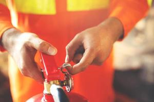 Fireman hand holding fire extinguisher. available in emergencies conflagration damage background. Safety concept. photo