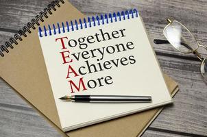 together everyone achieves more words on white notepad and glasses photo