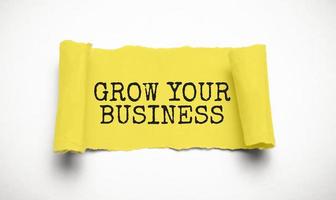 GROW YOUR BUSINESS text on torn paper , yellow background photo