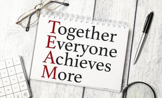 together everyone achieves more words and calculator, pen and glasses on wooden background photo