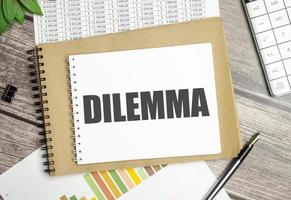 On the table charts, calculator and notebook with the inscription DILEMMA photo