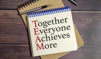 together everyone achieves more words on wooden background photo