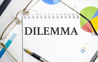 DILEMMA word on notepad with glasses and chart photo
