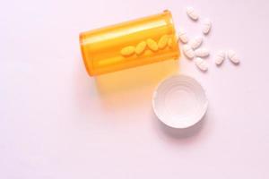 Oval pills and orange pill bottles were spread out on the white tabletop. photo