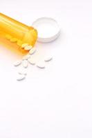 Oval pills and orange pill bottles were spread out on the white tabletop. photo