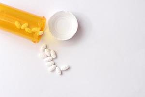 Oval pills and orange pill bottles were spread out on the white tabletop. photo