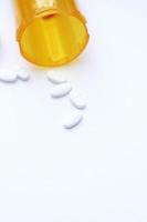 Oval pills and orange pill bottles were spread out on the white tabletop. photo