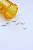 Oval pills and orange pill bottles were spread out on the white tabletop. photo