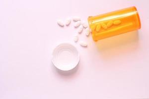 Oval pills and orange pill bottles were spread out on the white tabletop. photo