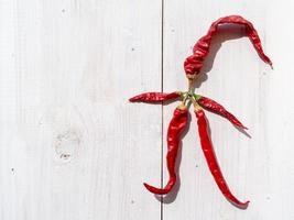 Funny man made of dry red hot pepper on a white wooden table, vegetable design background photo