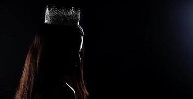 retrato del concurso de belleza miss pageant en vestido largo de baile de noche de lentejuelas con corona de diamantes de luz brillante, exposición de silueta baja clave con cortina, iluminación de estudio fondo oscuro dramático foto