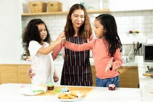 Group of Diverse Family, Asian and Arab Preschool African Arab kid person make Cake cooking in kitchen, Mother prepare decoration pretty with fun educate on snack. Cream mess all over face, copy space photo