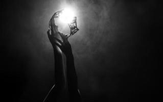 Silhouette abstract of two hands try to reach Diamond Crown as Miss Beauty Queen Pageant Contest as final competition, finale winner moment. Backlit smoke low exposure dark background copy space photo