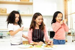 Group of Diverse Family, Asian and Arab Preschool African Arab kid person make Cake cooking in kitchen, Mother prepare decoration pretty with fun educate on snack. Cream mess all over face, copy space photo