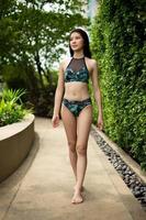 Beautiful cute Girl wear green swim suit Bikini, Asian woman walk and feel relaxing in flower garden in Resort spa hotel on travel vacation holidays, copy space photo