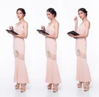 Full length body of Asian beautiful woman wear Pink evening sequin gown, working digital tablet photo