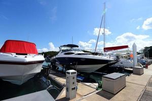 muchos yates de lujo flotan en un mar cristalino en el club de marina bay, un costoso barco privado mantiene la calma en el muelle de atraque bajo el cielo azul del verano océano verde foto