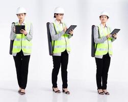 20 años de longitud completa, joven ingeniero de raza mixta, arquitecta, mujer cliente, que parece trabajar duro, usa una gran tableta de casco de seguridad. Los soportes femeninos de la oficina sienten una sonrisa feliz sobre un fondo blanco aislado foto