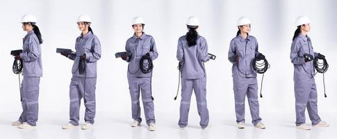 Mujer electricista ingeniera de raza mixta de longitud completa de los años 20, vista frontal trasera de 360 grados, con uniforme gris. Contratista hembra mantenga cable de enchufe eléctrico sonrisa feliz sobre fondo blanco aislado foto