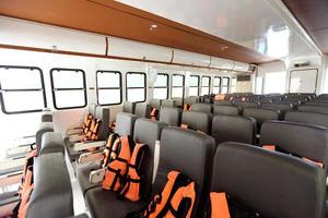 Many Seats row inside luxury cruise ferry with orange life vest jackets for Tourist to use to swim in Ocean sea and snorkeling underwater trip and safety first during transport photo