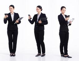 joven mujer caucásica profesora estudiante abogada de 20 años de duración, que usa un teléfono celular inteligente, usa un blazer formal negro y zapatos. Los soportes femeninos de la oficina sienten una sonrisa feliz sobre un fondo blanco aislado foto