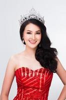 retrato del concurso miss pageant en vestido de noche de lentejuelas rojas asiáticas con banda de corona de diamantes plateados, peinado de cara de maquillaje de moda, iluminación de estudio fondo blanco espacio de copia aislado foto