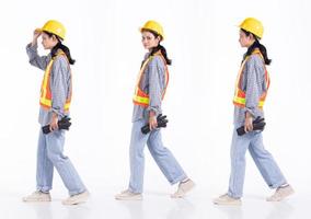 Full length 20s young Mix Race engineer contractor Woman, walking forward left right, wear safety vast hardhat gloves. Office female stands feels smile happy over white background isolated photo