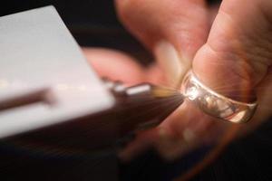 Golden Ring in hands ready to check real or not with Diamond Tester Gemstone Selector Gems LED Indicator Jewelry kits Test, Portable electronic device to peep quick, precise, safe, selective focus photo