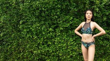 Beautiful cute Girl wear green swim suit Bikini, Asian woman walk and feel relaxing in flower garden in Resort spa hotel on travel vacation holidays, copy space photo