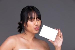 mujer india asiática muestra una hermosa sonrisa labios felices, sostiene una caja vacía en blanco para el tratamiento de la piel foto