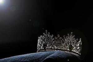 Diamond Silver Crown for Miss Pageant Beauty Contest, Crystal Tiara jewelry decorated gems stone and abstract dark background on black velvet fabric cloth, Macro photography copy space for text logo photo