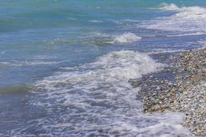 las olas del mar corren hacia la orilla de guijarros. línea de la costa del mar plack foto
