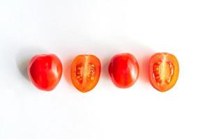 Ripe red cherry tomatos in a row. Whole and halves of vegatbles on white background photo