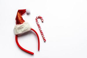 santa hat and candy cane on white background. Creative new year flat lay with copy space. Minimalistic style photo