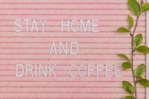 Lettreing booard with quote stay home and drink coffee decorated with spring branch with green fresh leaves. Spring motivation background photo