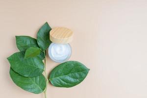 frosted glass jar with cream of natural incgedients. Herbal aromatherapy and skincare. Green leaves on the background photo