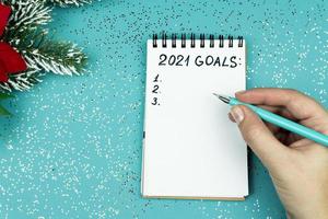 Female hand writing 2021 goals for new year. Resolutions list. photo