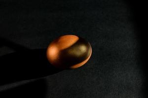 Golden egg on black background . Minimal style backdrop with copy space. photo